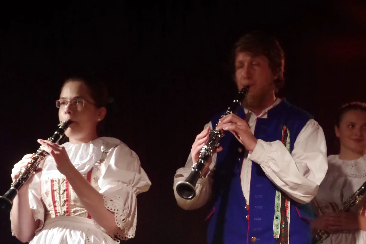 Two clarinet players in traditional Bohemian and Moravian folk costume performing on a dark stage, representative of the instruments in a Czech cimbalom band