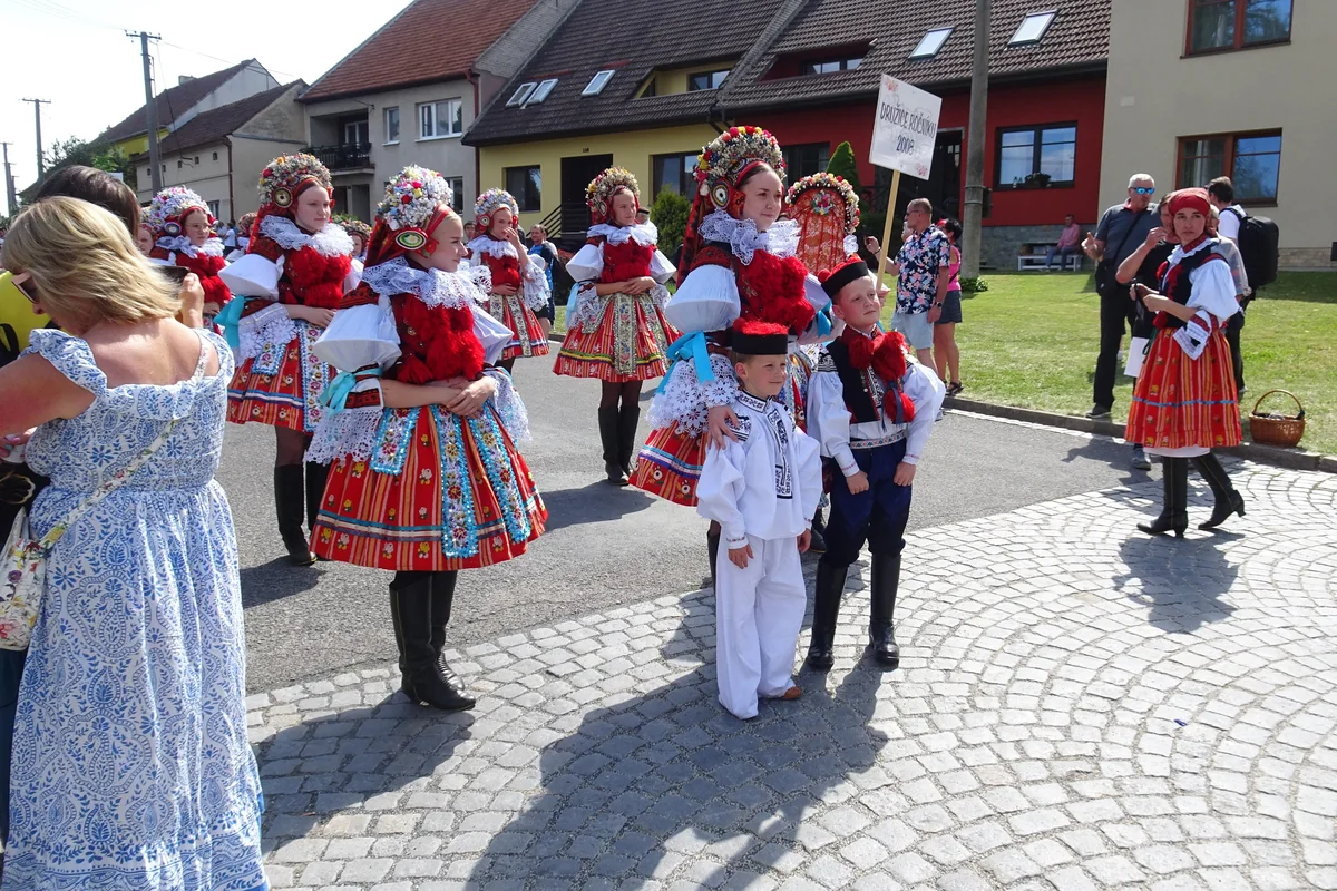 Children and performers in vivid red Moravian Slovácko folk costume at a village procession, representative of Moravian folk dress generally
