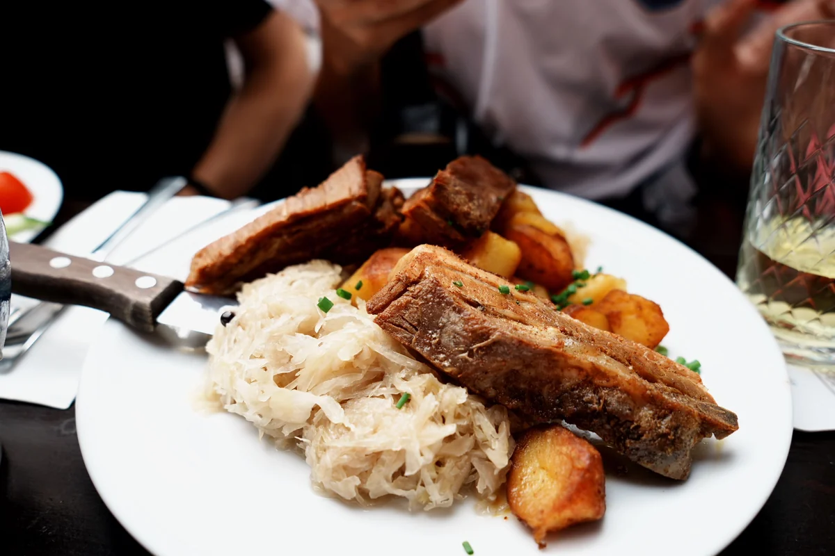 A plate of roast pork, sauerkraut and potatoes, representative of a hearty traditional Central European dinner